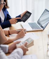 Real estate agent helping senior couple to calculate mortgage payment and down payment